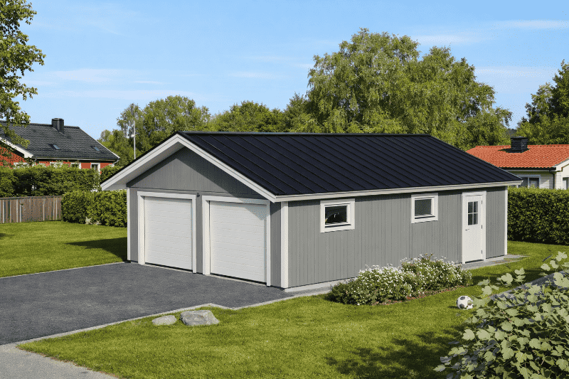 Dubbelgarage med grå fasad, mörkt tak, två garageportar och fönster